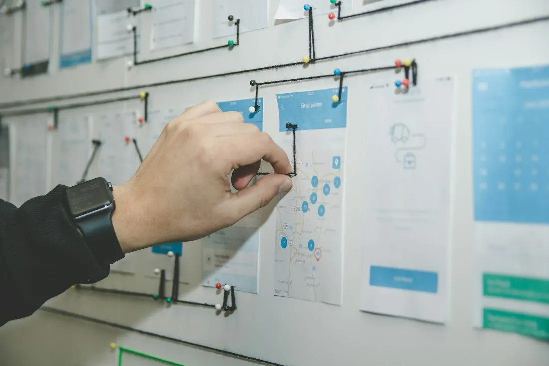 A person arranging task notes on a glass planning board