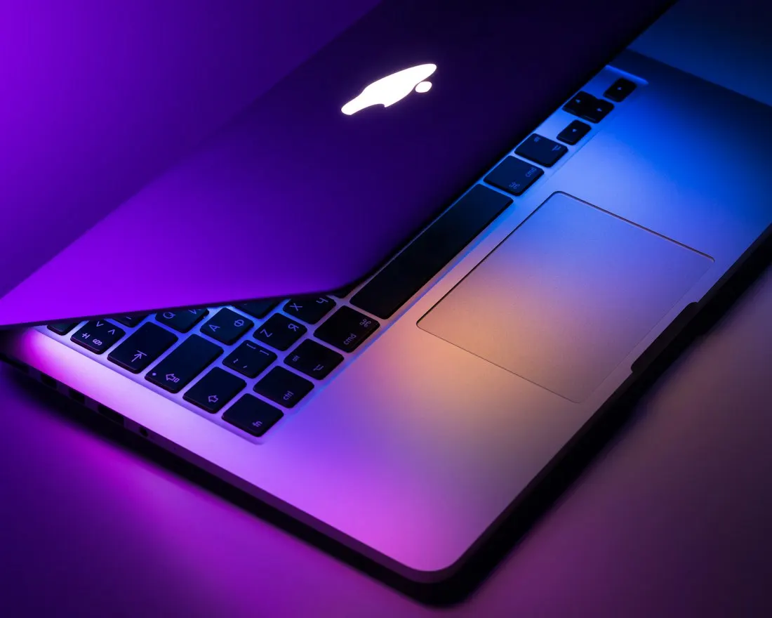 A laptop keyboard illuminated with purple light