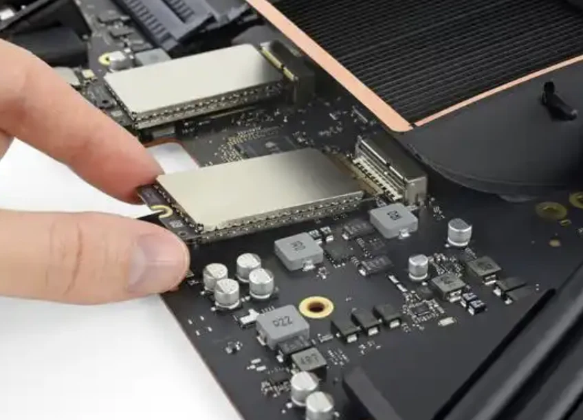 A hand removing a storage module from an open laptop