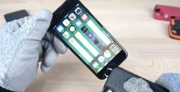 Gloved hands wiping the front of a smartphone