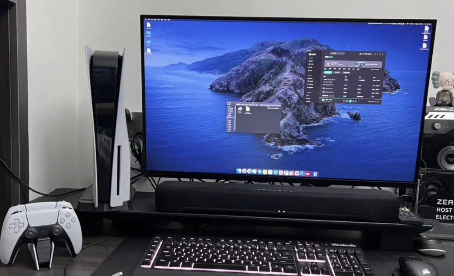 A desktop monitor with a soundbar and gaming equipment