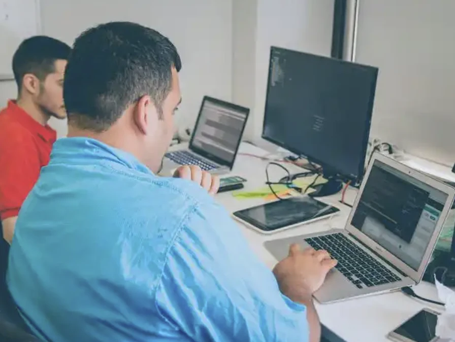 Two people working together with laptops and an external monitor