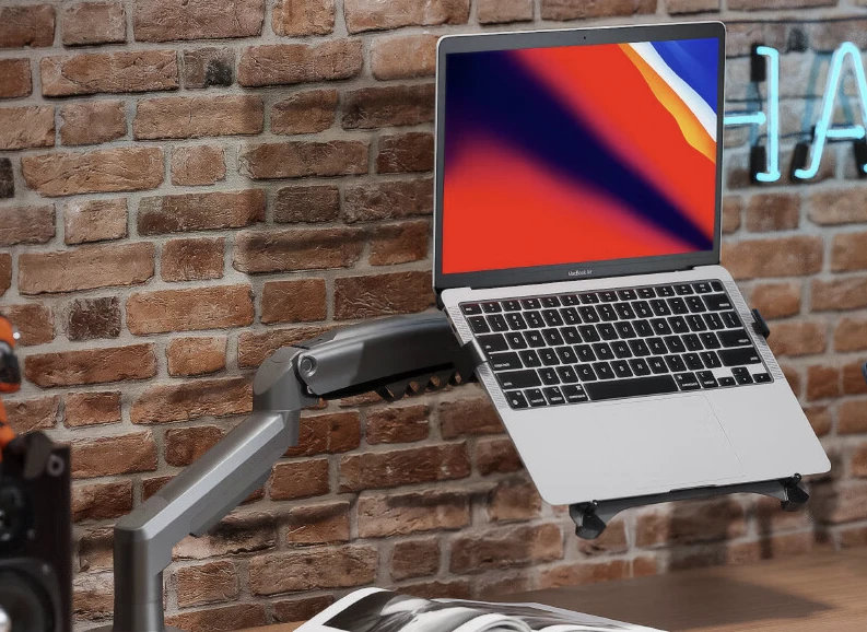 A laptop raised above a desk on an adjustable support arm